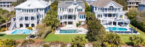 A large, two-story house with a swimming pool, a tennis court, and a well-maintained lawn.