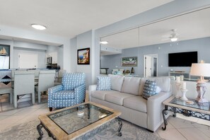 Un salon avec un canapé, des fauteuils, une table basse et un téléviseur.