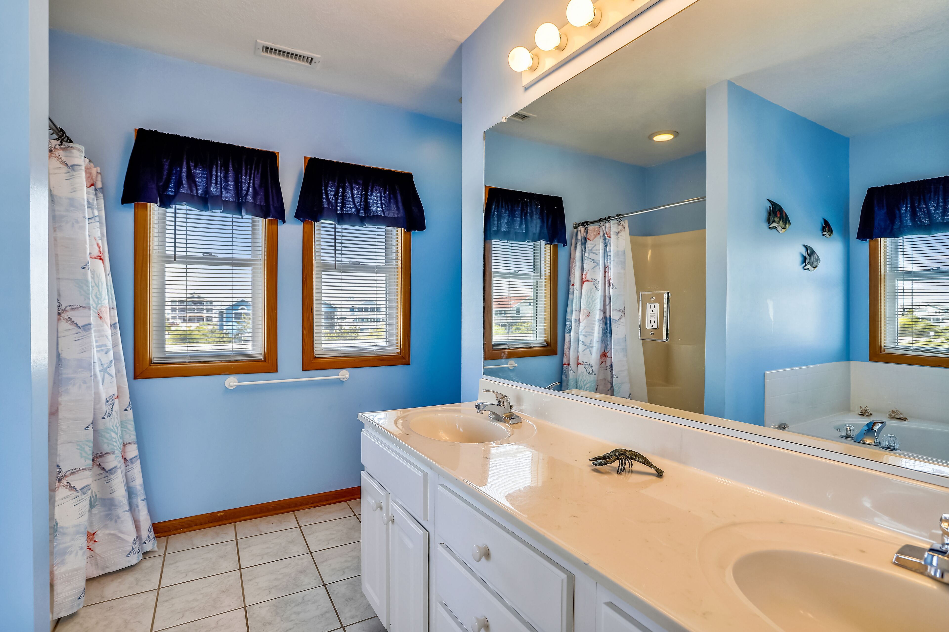 A bathroom with a large mirror, a sink, and a shower.