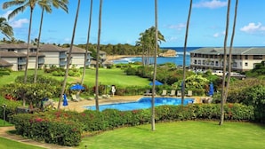 A resort with a swimming pool, palm trees, and ocean views. - Poipu Sands 123 Beautiful Ocean View AC Suite Paradise (Koloa)