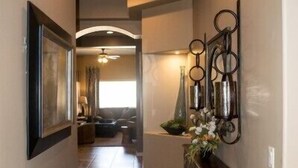 A hallway with a wooden cabinet, a framed picture, and decorative wall sconces.