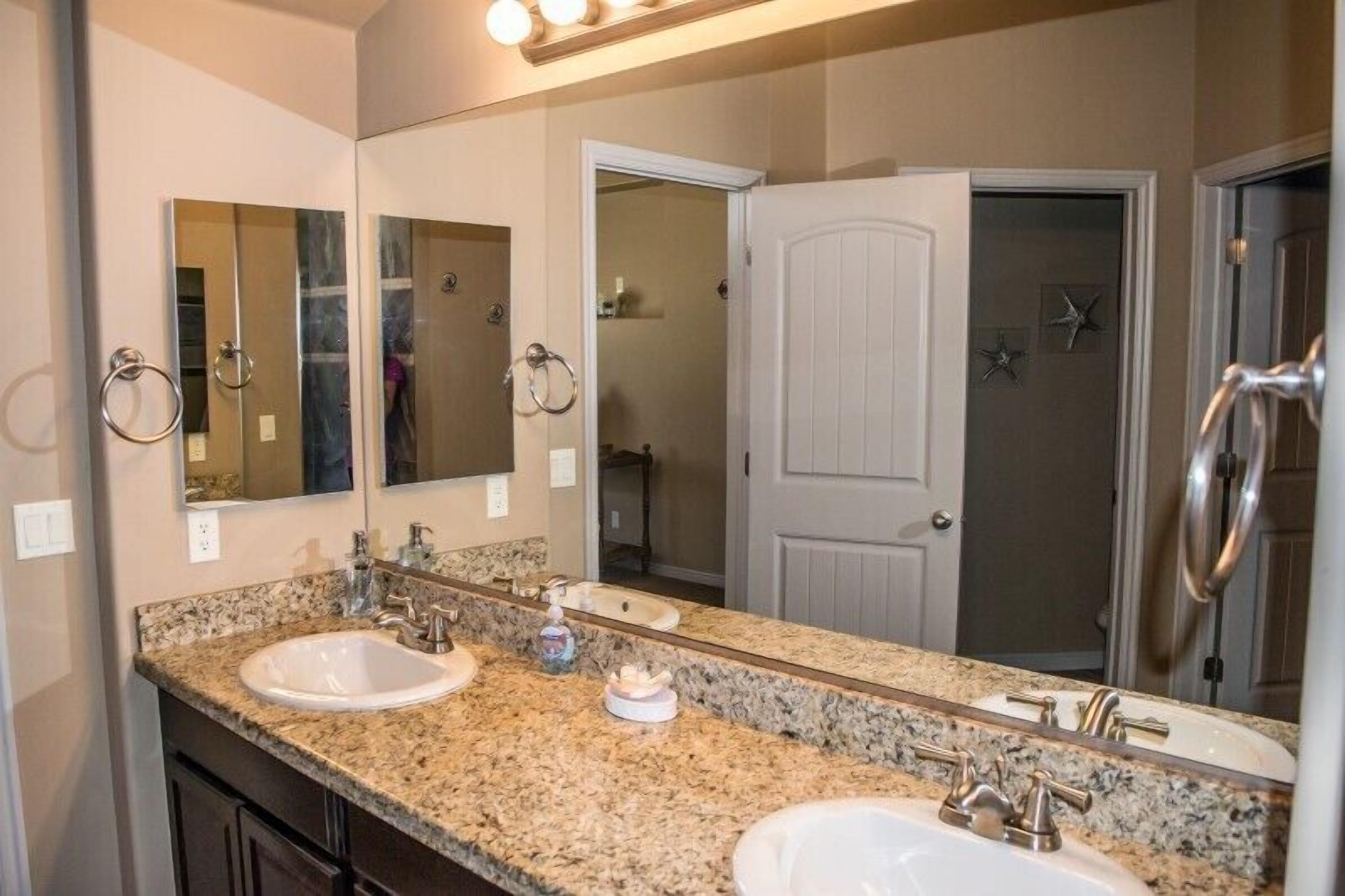 A bathroom with two sinks, a large mirror, and a shower area.
