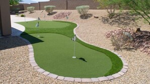 A miniature golf course with a green putting area, flags, and a curved path.