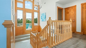 A spacious room with a wooden staircase, large windows, and a view of the outdoors. - As Time Goes By: Dog-friendly, Elevator, Pool, Hot Tub (Corolla)