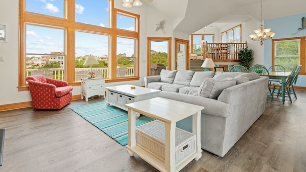 A spacious living room with a large gray sofa, a red patterned armchair, and a white coffee table. - As Time Goes By: Dog-friendly, Elevator, Pool, Hot Tub (Corolla)