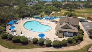 A swimming pool surrounded by lounge chairs and umbrellas, with a building in the background. - As Time Goes By: Dog-friendly, Elevator, Pool, Hot Tub (Corolla)