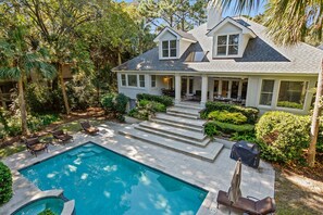 Une maison à deux étages avec une piscine, un espace extérieur aménagé pour se détendre et un jardin bien entretenu.