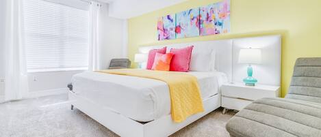 A modern bedroom with a large bed, a bedside table with a lamp, and a colorful abstract painting on the wall.