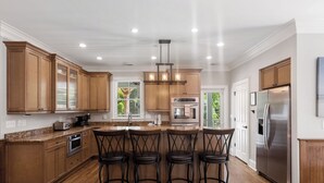 A spacious kitchen with wooden cabinets, a stainless steel refrigerator, and a bar area with stools.