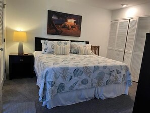 A bedroom with a bed, nightstands, a lamp, a painting, and a closet.