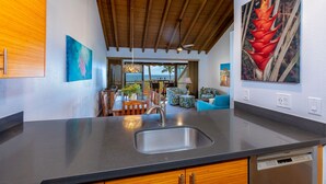 Una cocina moderna con una isla grande, vigas de madera en el techo y obras de arte en las paredes.