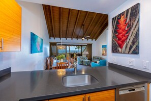 Una cucina moderna con una grande isola, travi in legno a soffitto e opere d'arte alle pareti.