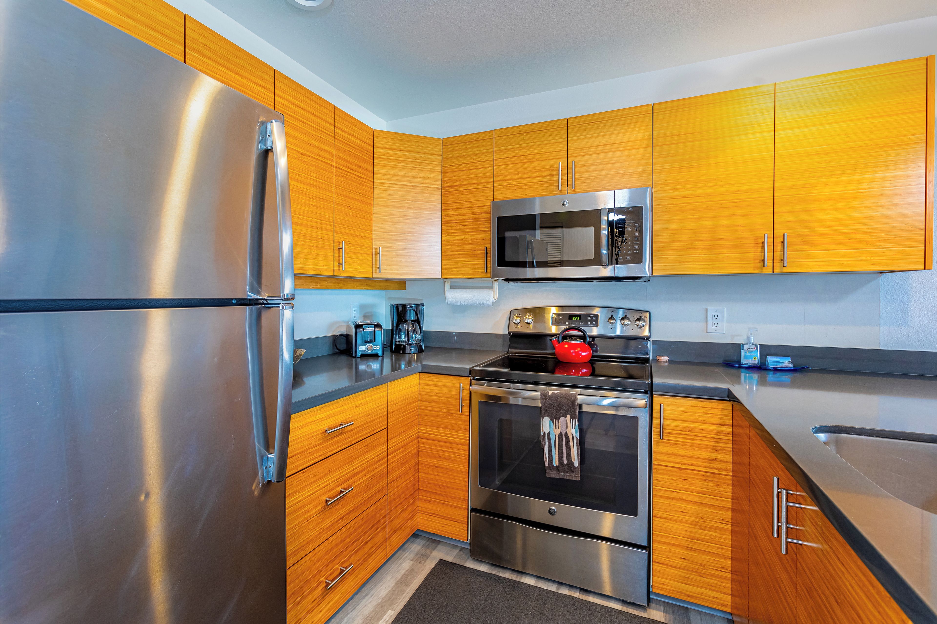 A modern kitchen with stainless steel appliances, wooden cabinets, and a microwave.