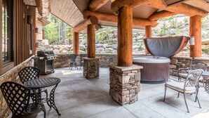 Een terras buiten met stenen zuilen, een jacuzzi en zitplaatsen.