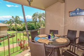 Un balcon avec une table, des chaises et une pancarte sur laquelle on peut lire : « LIVE ALOHA ».