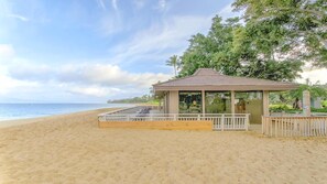 Un belvédère au bord de la plage, doté d’une terrasse en bois et d’une structure vitrée, offrant une vue sur l’océan.
