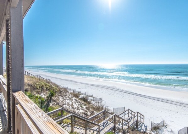 A beach view with a wooden staircase leading down to the shore.