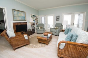 A living room with wicker furniture, a fireplace, and a television.