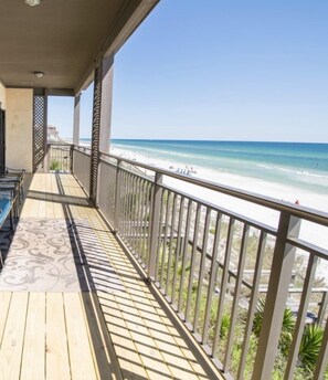 A wooden deck with a railing overlooking a beach.