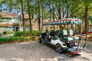 Een golftrolley geparkeerd op een verharde oprit, met een huis op de achtergrond.