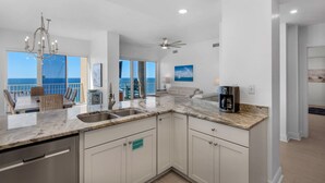 A modern kitchen with a marble countertop, stainless steel appliances, and a view of the ocean.