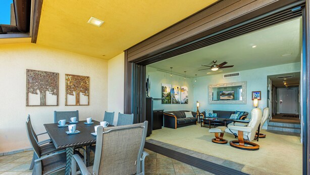 A dining area with a table and chairs, a sofa, and a ceiling fan. - Beachfront Living - Makena Surf E-202 - Mesmerizing Views & Tropical Landscapes (Makena, Maui)