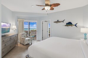 A bedroom with a bed, a TV, a dresser, a chair, and a ceiling fan. - 6-Seat Golf Cart ~ Beach Front ~ Private Balcony (Miramar Beach)