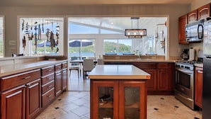 A kitchen with wooden cabinets, a central island, a stove, and a refrigerator.