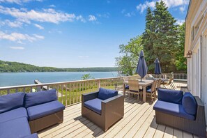 Una terraza con mobiliario de mimbre y vistas a un lago.