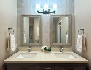 A bathroom with two sinks, a large mirror, and a potted plant.