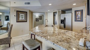 A kitchen with a marble countertop, stainless steel appliances, and framed artwork on the walls.