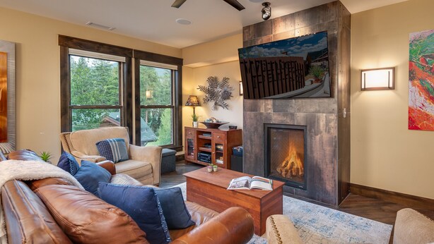 A cozy living room with a fireplace, leather sofas, and a bookshelf.