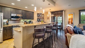 A modern kitchen with dark wood cabinets, stainless steel appliances, and a central island with bar stools.
