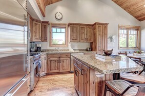 Gourmet display kitchen with Viking refrigerator, 5-burner gas stove, granite counters, and island with 4-bar seats