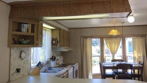 Una cocina con armarios de madera, un lavamanos y una zona de comedor con una mesa y sillas.