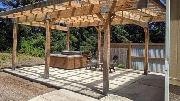 Una pérgola de madera con una parrilla incorporada y zona de estar.