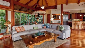 A spacious living room with a large sectional sofa, wooden coffee table, and a ceiling fan.