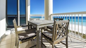 Un balcón con mesa y sillas de madera, con vista a la playa.