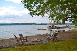 A lakeside view with wooden chairs, a dock, and a small building. - Heart's Desire: Great Sunset Views (Canandaigua)