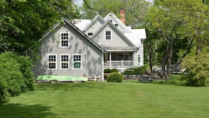 A two-story house with a porch, surrounded by a well-maintained lawn and trees. - Aurora Escape: "Spectacular Design Awaits You!" (Aurora)