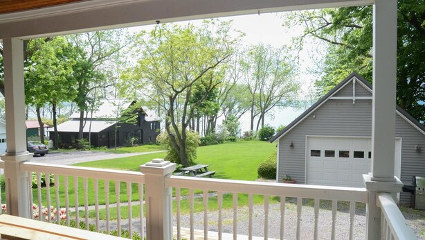 A covered porch with a view of a grassy yard, a small shed, and a garage. - Aurora Escape: "Spectacular Design Awaits You!" (Aurora)