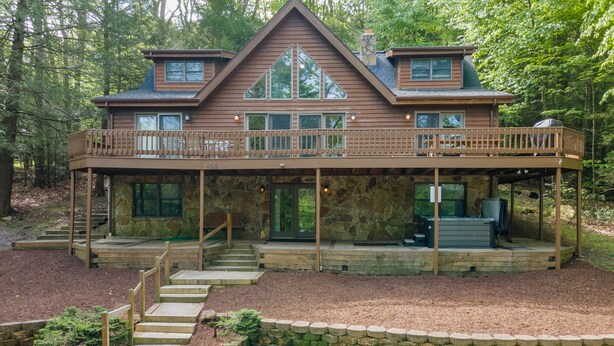 A two-story wooden cabin with a balcony, stone foundation, and a fireplace. - Deep Creek Dog Friendly Cabin w/ Dock & Fireplace (Swanton)