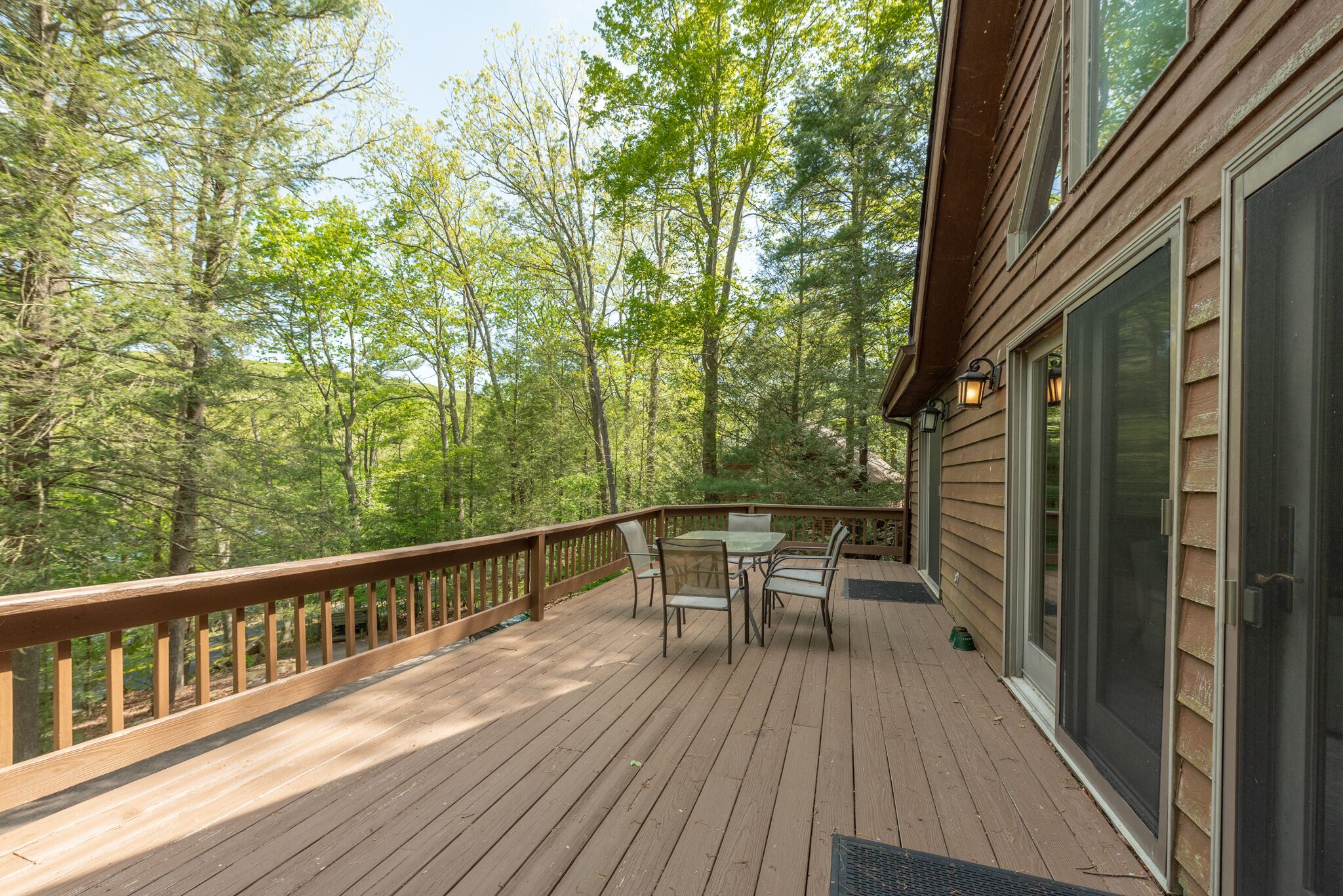 Une terrasse en bois avec une table et des chaises, entourée d’arbres.