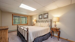 A bedroom with a bed, a window with blinds, a bedside table with a lamp, and two framed pictures on the wall. - Deep Creek Dog Friendly Cabin w/ Dock & Fireplace (Swanton)