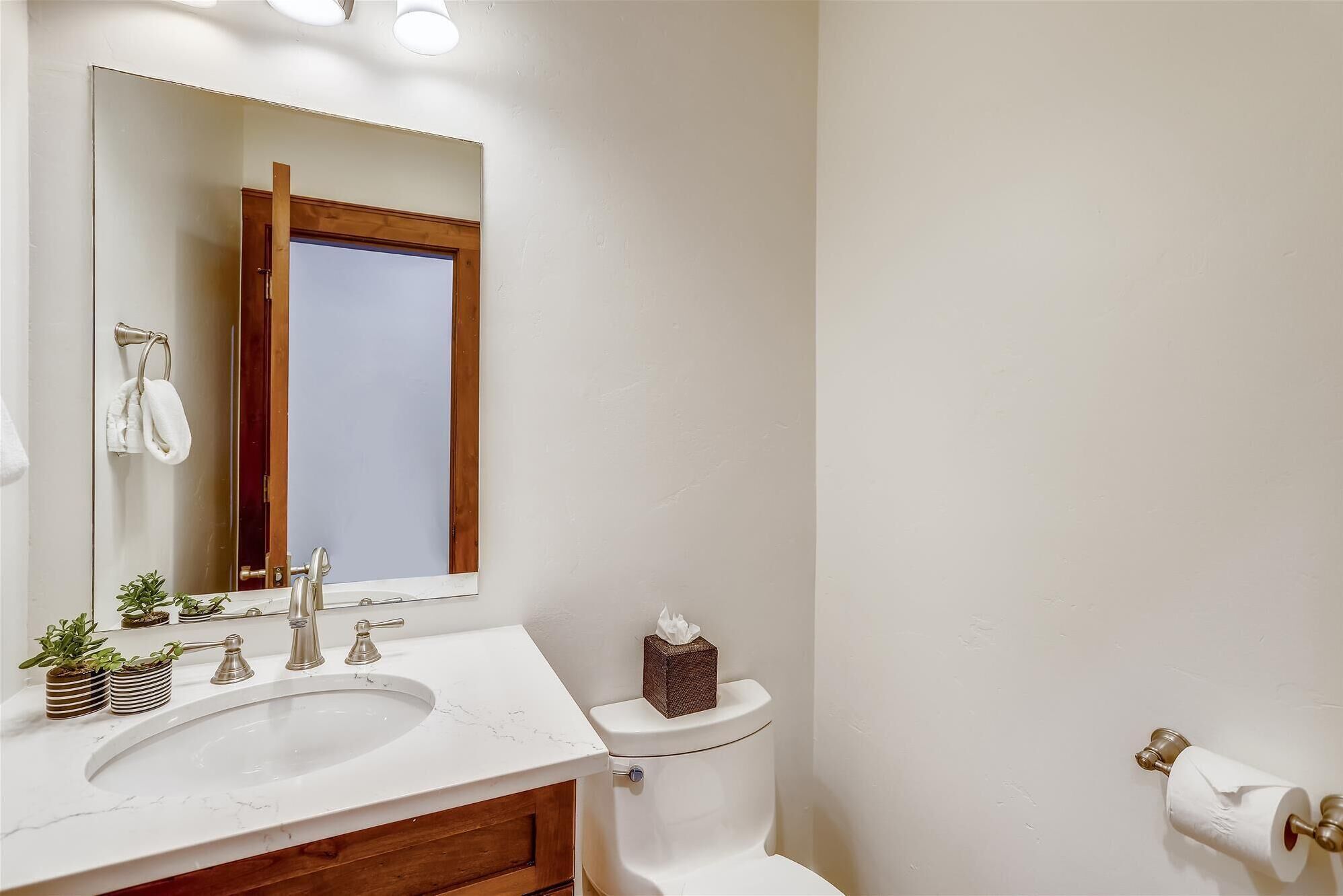A bathroom with a white sink, a mirror, a toilet, and a towel rack.