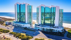 Een modern hotel met een golvend gevelontwerp, grote glasramen en een ligging aan het strand.