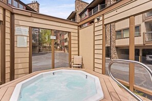 A hot tub with a wooden deck, a chair, and a sign indicating it's a hotel.