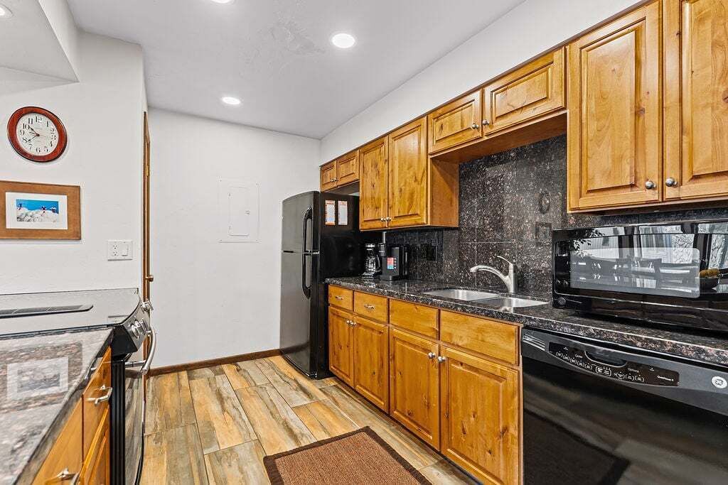 A kitchen with wooden cabinets, a black refrigerator, a microwave, and a dishwasher.