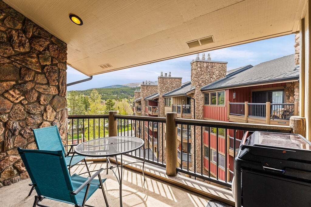 A balcony with a stone wall, a glass table, and chairs.