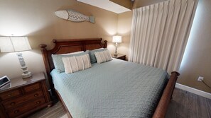 Quarto com cabeceira de madeira, colcha acolchoada e duas luminárias de apoio.